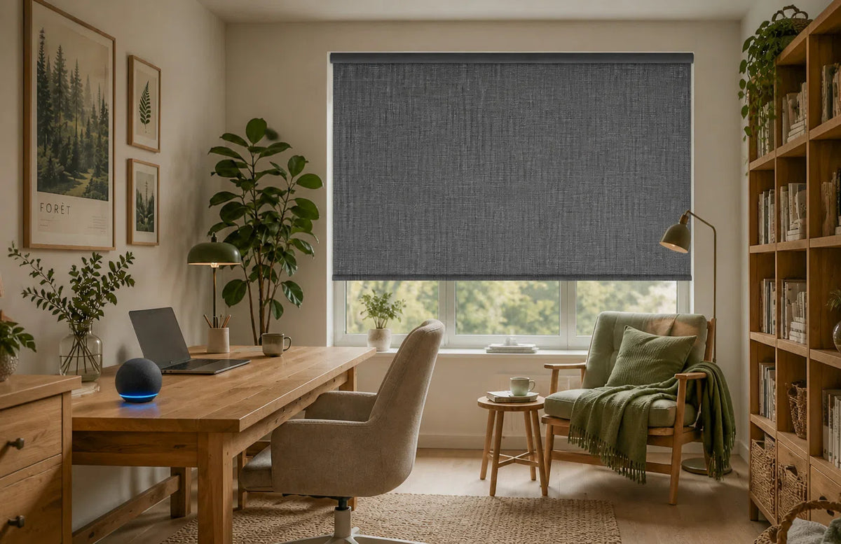 Motorized blackout roller shade with textured woven fabric partially lowered over a home office window